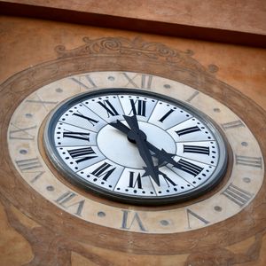 Close-up of an ornate vintage clock displaying Roman numerals on a decorative wall.